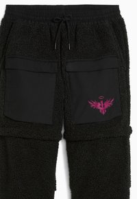 Zwarte fleece joggers met zwarte nylon zakken en een roze adelaar grafisch. Voorzien van een elastische tailleband met trekkoord en een gestructureerde stof.
