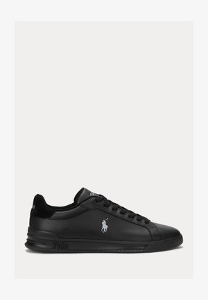 Sorte lærersneakers med en glat overflade, flad gummisål, snørebåndsdesign og kontrastlogo på siden.