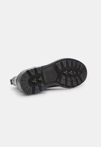 Suola di scarpa in gomma nera con scanalature profonde, motivi texture e un tallone rinforzato. Presenta un design elegante e curvo per migliorare la presa.