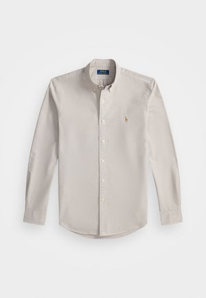 Camisa de botón de manga larga en gris claro, hecha de algodón. Cuenta con un cuello extendido, botones frontales y un pequeño logo bordado en el pecho.