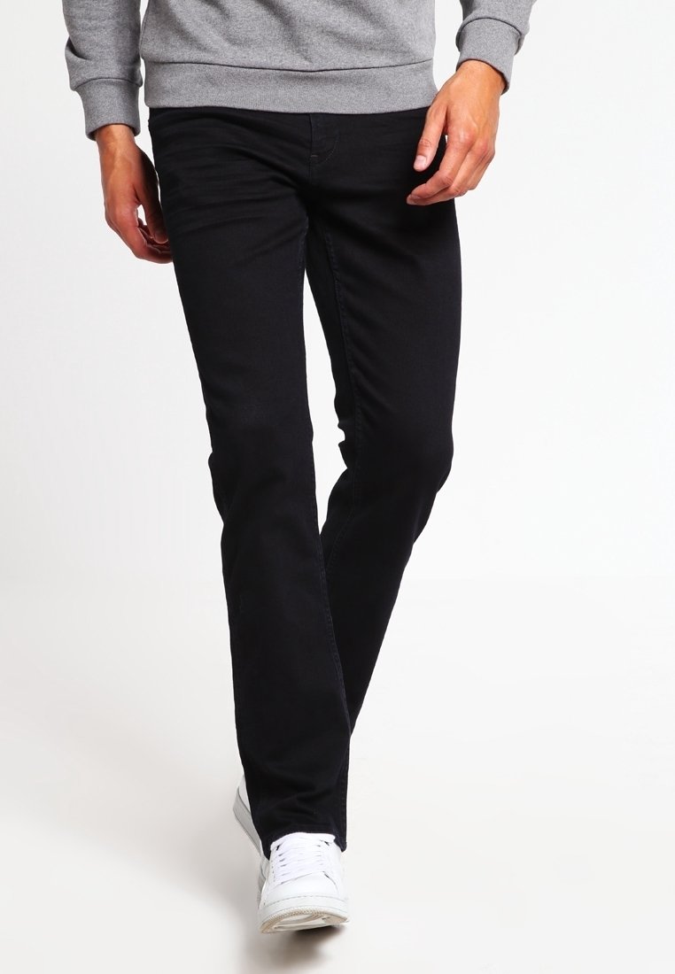 Czarne dżinsy o prostym kroju, zestawione z szarym swetrem. Dżinsy mają klasyczny pięciokieszeniowy krój i minimalną ilość elementów metalowych.