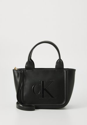 Borsa a tracolla in pelle nera con logo "cK" in rilievo. Presenta manici corti e una tracolla regolabile. Tessuto liscio, forma strutturata.