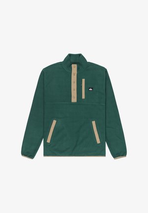 Vihreä fleece-pullover beigeilla yksityiskohdilla, jossa on korkea kaulus, nappilista, sivutaskut ja vetoketjullinen rintatasku.