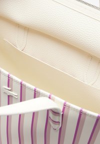Bolso blanco de cuero texturizado, con un interior de acabado suave. El diseño exterior presenta rayas moradas y rosas con asas a juego.