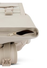 Beige színű keresztbody táska sima műbőr külső borítással, cipzáras zárással, állítható pántokkal és oldalán klipszes részletekkel a biztonságos tárolás érdekében.