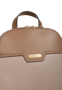 Borsa a mano in pelle marrone con superficie testurizzata, parte superiore arrotondata e dettagli in oro. Presenta una placca con il logo del marchio sulla parte anteriore.