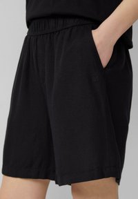 Zwarte katoenen shorts met een elastische tailleband, zijzakken en een subtiele logo-detail. Zachte textuur en een ontspannen pasvorm.