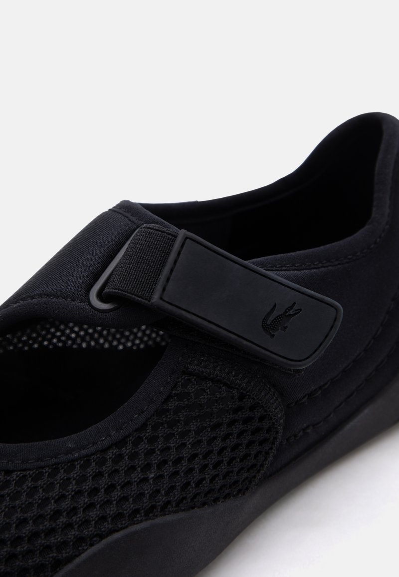 Scarpa nera in mesh traspirante con cinturino in Velcro regolabile con un piccolo logo a rilievo sul lato.