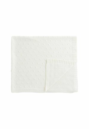 Weiß gestrickte Decke mit einem strukturierten Tupfenmuster und einem gerippten Rand an einer Seite. Weiches Stoffmaterial bietet Wärme.
