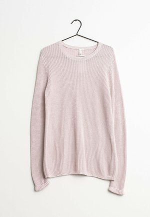 Pull en tricot rose clair à manches longues suspendu sur un cintre noir contre un fond blanc uni.