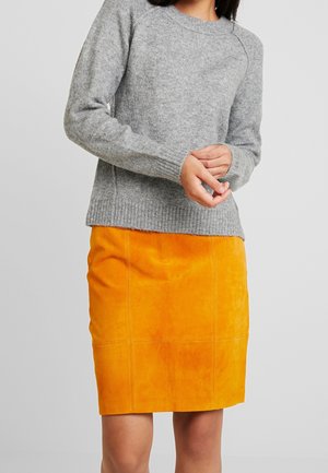 Maglione grigio lavorato a maglia con orlo e polsini a costine abbinato a una gonna a tubino in suede arancione con cuciture verticali e una texture morbida.