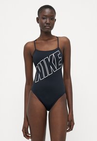 Svart heldrakt med tynne stropper, med en stor hvit Nike-logo diagonalt over forsiden, glatt tekstur og høyt utskårne ben.