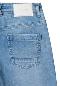 Jean en denim bleu clair montrant une poche arrière et un patch de marque en cuir blanc avec un texte en relief à la taille.