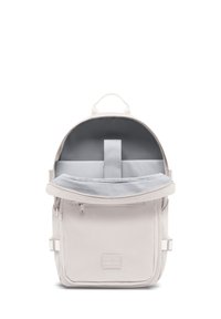 Sac à dos en tissu gris clair avec une poignée supérieure, une poche zippée à l'avant et un compartiment intérieur rembourré. Présente un patch logo à l'avant.