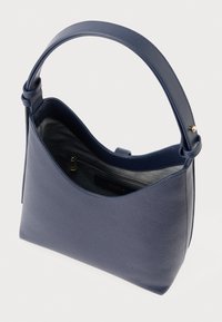 Zila ādas soma ar gludu faktūru, izliekta augša un vienu siksnu. Iekšpusē ir rāvējslēdzēja kabata. Minimālistisks dizains.