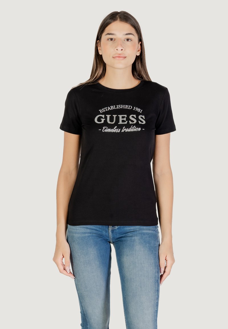 T-shirt nero in cotone con maniche corte e scollatura rotonda, con un logo grigio "GUESS" e il testo "Established 1981" sul davanti.
