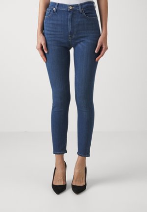 Jean skinny bleu taille haute en denim, avec un design classique à cinq poches et une texture légèrement décolorée, dotée d'un ourlet propre.
