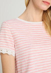 Gestreept t-shirt in roze en wit met een ronde halslijn en kantafwerking op de mouwen. Katoenen stof met een zachte textuur.
