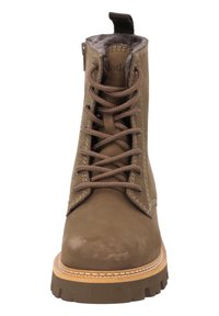 Brązowy zamszowy botek za kostkę z sznurowanym zapięciem, wyściełanym kołnierzem i grubą gumową podeszwą; posiada kontrastowe przeszycia i uchwyt na górze.