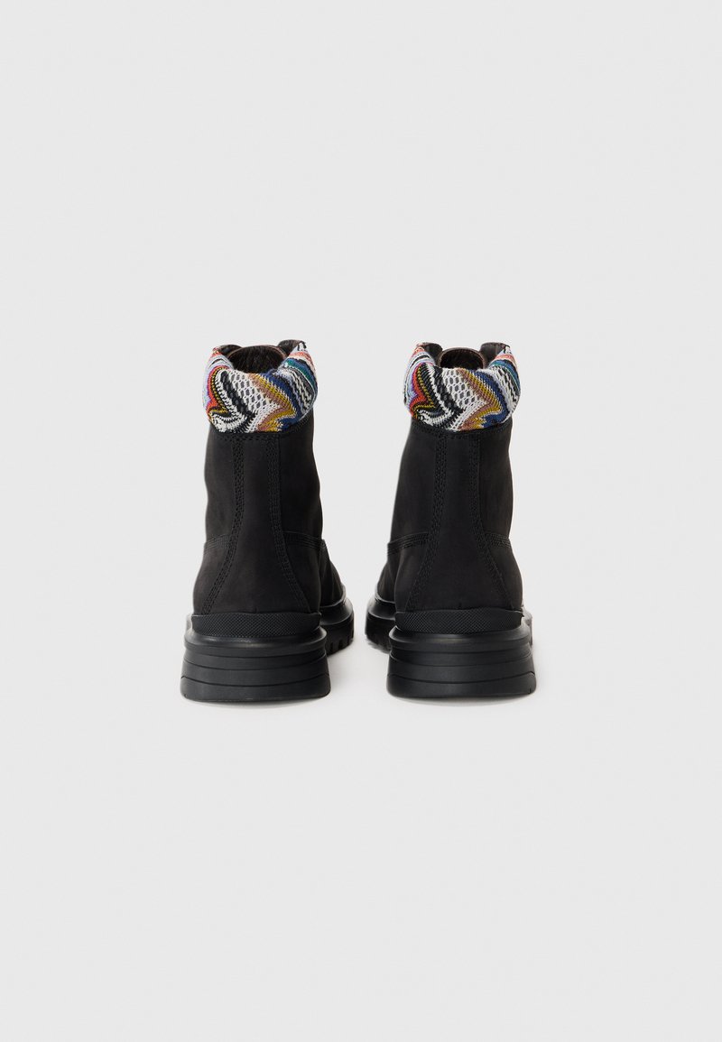 Svarta ankelstövlar med en texturerad mockaovandel, prydda med en färgglad mönstrad stickad krage och en kraftig gummisula.