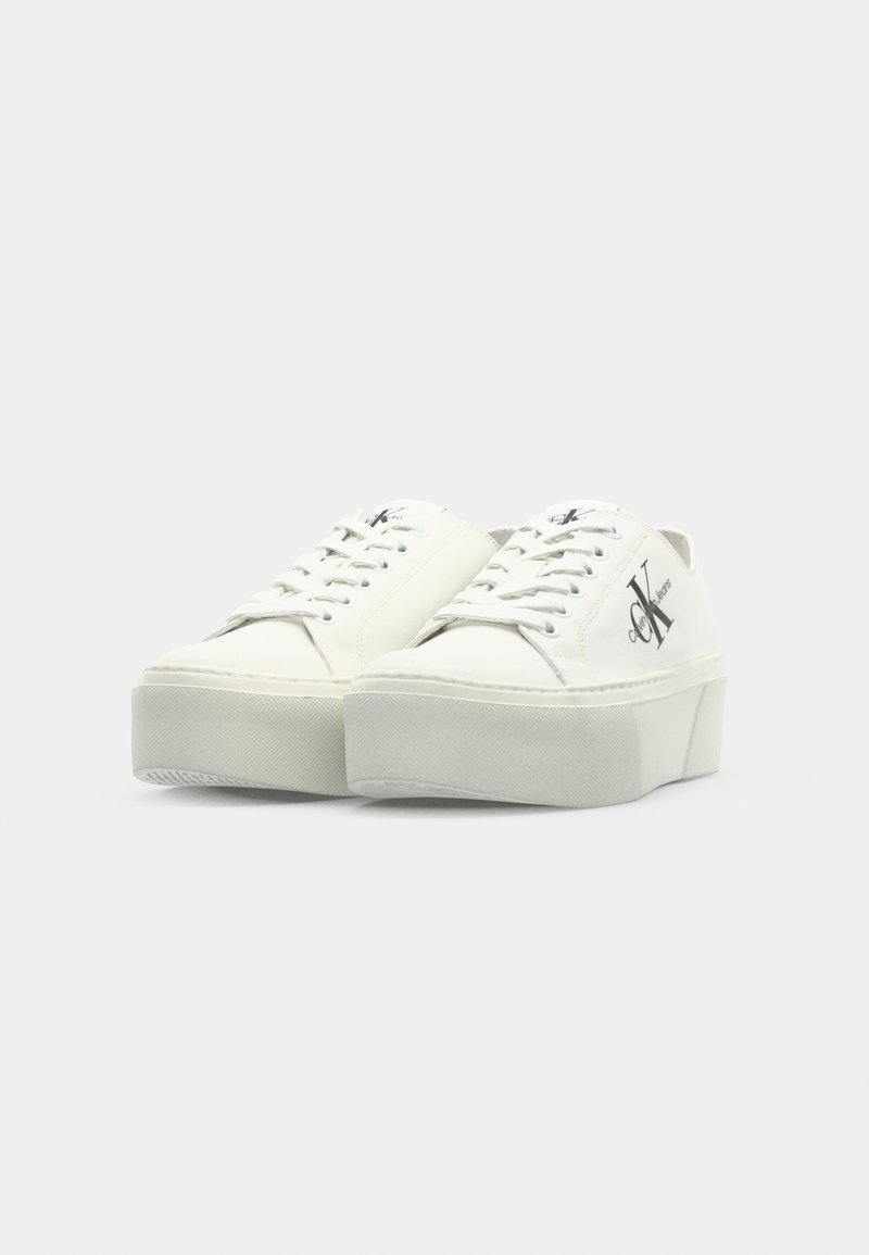 Baskets plateformes blanches avec semelle en caoutchouc texturée, col rembourré et lacets ton sur ton. Présente un logo imprimé sur le côté.