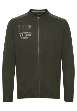 Sötétzöld, cipzáros kardigán texturált kötött anyagból, bordás mandzsettákkal és szegéllyel. Bal mellrészen fehér és színes hímzett szöveggel rendelkezik.