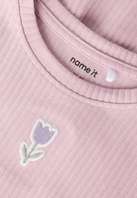 Ροζ ριμπ μπλούζα με στρογγυλή λαιμόκοψη και κεντητό λουλούδι λεβάντας με πράσινα φύλλα στο μπροστινό μέρος. Ορατή ετικέτα στο εσωτερικό.