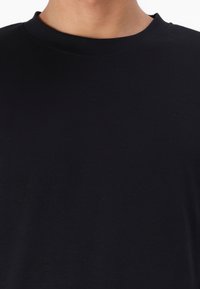 Svart crew-neck t-skjorte laget av bomull. Har en jevn tekstur uten synlige mønstre eller aksenter. Enkel og klassisk design.