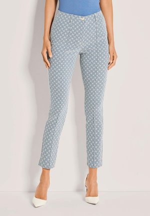 Hellblaue gemusterte Hose aus glattem Stoff mit Rautendesign, schlanker Passform und mittelhoch sitzendem Bund, kombiniert mit weißen High Heels.