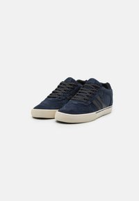 Navy suede sneakers with textured laces and rubber soles. Features two black stripes on the sides and a cushioned tongue.