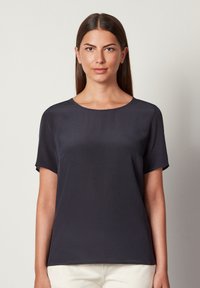 Marineblå kortærmet bluse med rund halsudskæring, glat tekstur og afslappet pasform. Minimalistisk design uden mønstre eller synlig hardware.