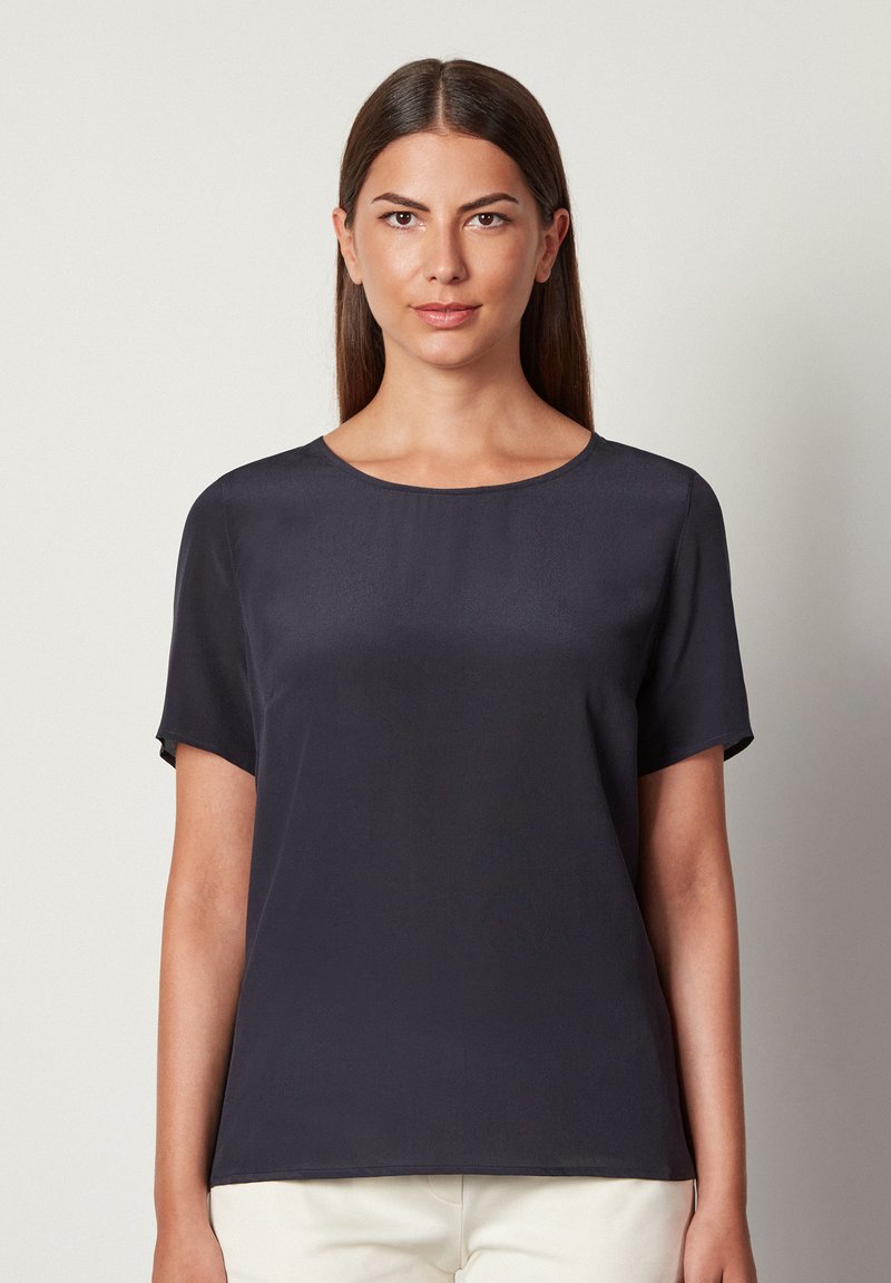 Marineblå kortærmet bluse med rund halsudskæring, glat tekstur og afslappet pasform. Minimalistisk design uden mønstre eller synlig hardware.