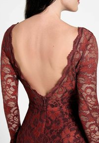 Robe en dentelle rouge à manches longues, dos plongeant en V, motif floral texturé et fermeture éclair dissimulée en bas du dos.