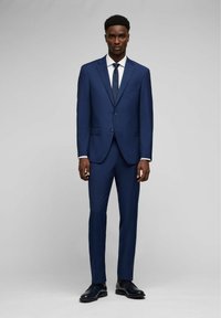 Completo blu da uomo con vestibilità slim. La giacca presenta due bottoni, rever a punta e una tasca sul petto. Abbinalo a una camicia bianca e una cravatta.