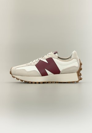 Baskets blanches et beiges avec une semelle épaisse et une semelle extérieure marron cloutée, avec un grand logo "N" bordeaux sur le côté.