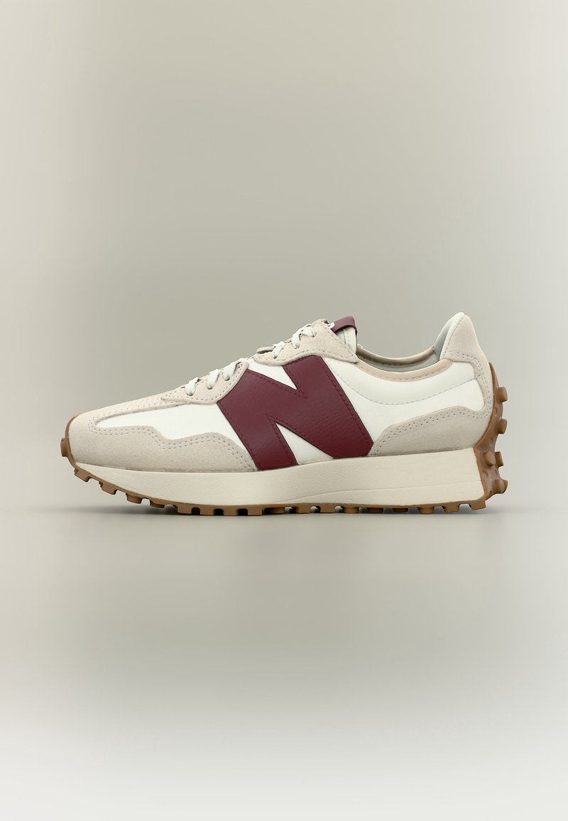 Baskets blanches et beiges avec une semelle épaisse et une semelle extérieure marron cloutée, avec un grand logo "N" bordeaux sur le côté.