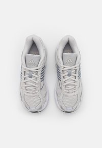 Svetle šedé sportovní boty s síťovanou tkání, texturovaným designem, bílou podrážkou a třemi modrými pruhy po stranách. Logo na jazyku.