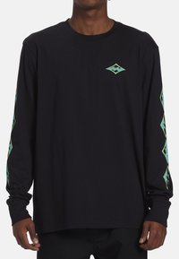 Sort langærmet t-shirt med grønt diamantgrafik på brystet og grønne detaljer på ærmerne. Lavet af blødt, tekstureret bomuldsstof.