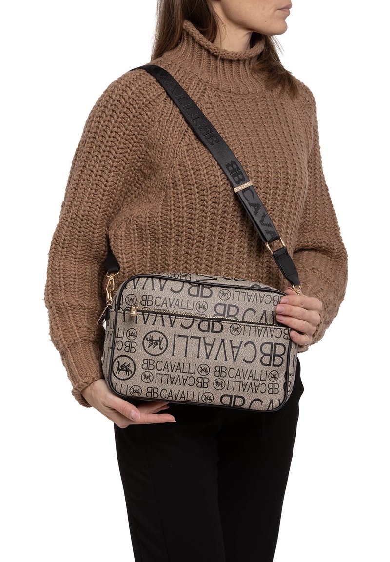 Borsa a spalla beige con logo Cavalli neri. Forma rettangolare, doppi scomparti con cerniera e tracolla nera regolabile con dettagli del logo.