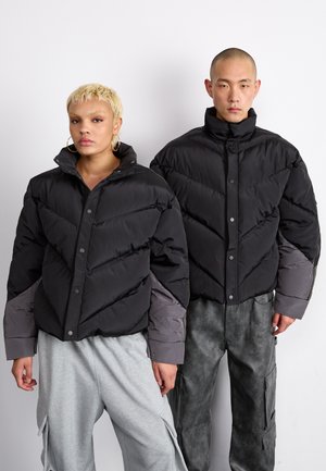 Črne puffer jakne z vzorcem quilt v obliki črke V, z sivimi akcenti na rokavih. Jakne imajo visoke ovratnike in pritisne gumbe.