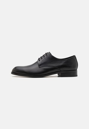 Scarpa Oxford in pelle nera con finitura liscia, punta arrotondata, cuciture minime e tacco basso. Design classico con lacci.