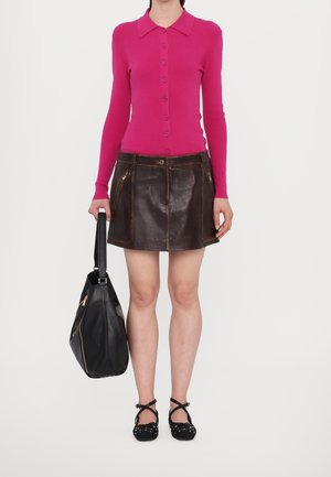 Fuchsia ribbed long-sleeve cardigan, brown leather mini skirt with zippered pockets, black handbag, and black shoes with white polka dots.