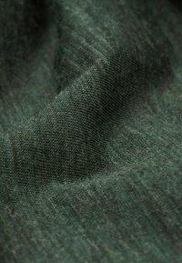 Pletená tkanina v tmavě zelené barvě s texturovanými vzory. Měkký, mírně elastický materiál, který vykazuje různé odstíny zelené pro prohloubení.