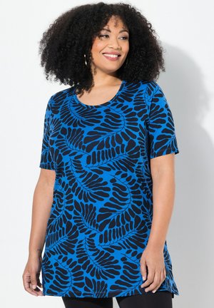Tunique bleue avec un motif de feuilles en noir, à manches courtes, col rond et coupe décontractée qui arrive en dessous des hanches.