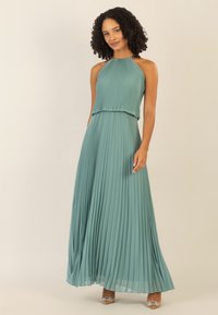 Türkisfarbiges, plissiertes Maxikleid mit Halterneck, fließendem Stoff und tailliertem Oberteil, das eine glatte Textur und eine elegante Silhouette aufweist.