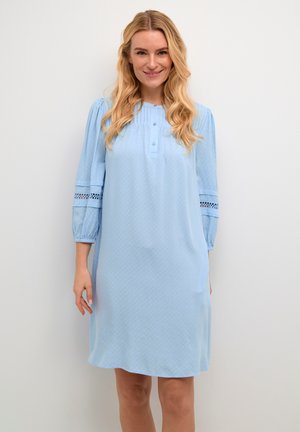 Abito azzurro chiaro con maniche a tre quarti, bottoni, tessuto texturizzato e dettagli in pizzo sulle maniche. Vestibilità morbida, design fino al ginocchio.