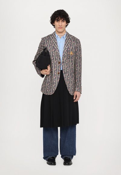 Multicolored floral-patterned blazer with stripes, light blue shirt, black skirt, and wide blue jeans. Black bag with strap in hand.