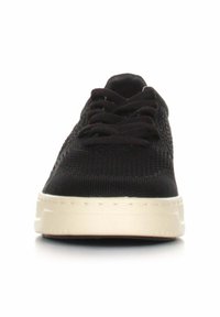 Sneaker nero in maglia con tomaia strutturata, suola in gomma bianca e classico design con lacci. Vista frontale che mostra la forma slanciata della scarpa.