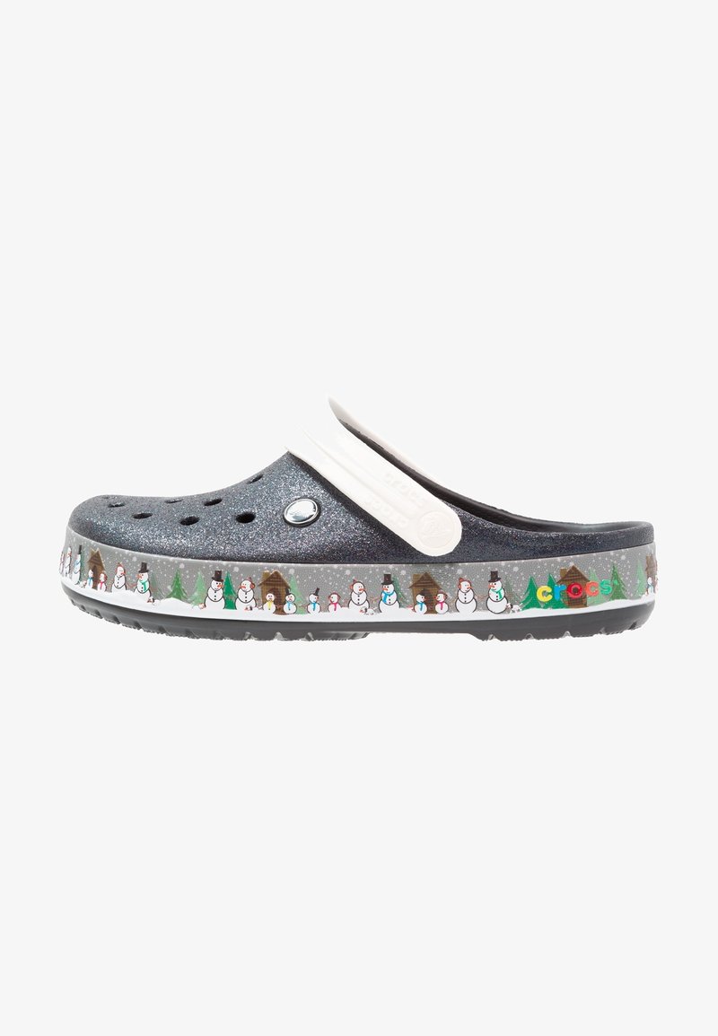 Sabot Crocs gris foncé pailleté avec bride blanche, décoré de bonhommes de neige, d'arbres et de chalets le long du bord de la semelle.