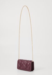 Burgundijas krāsas šūts crossbody soma ar zelta ķēdes siksnu. Mīksts materiāls, taisnstūra forma, ar izšūtu rakstu priekšpusē.